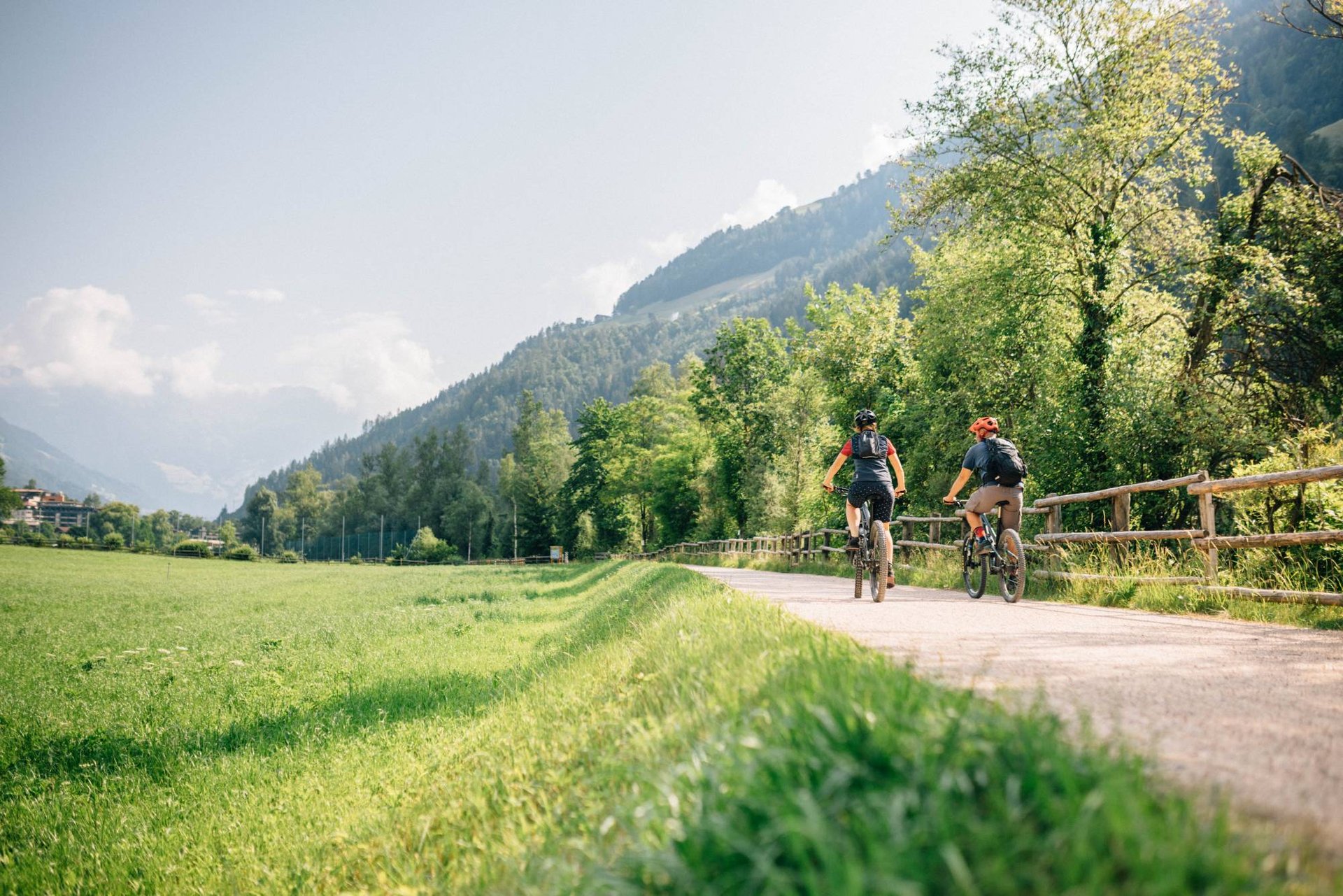 Radfahrende auf einem Weg neben einer grünen Wiese im Tal